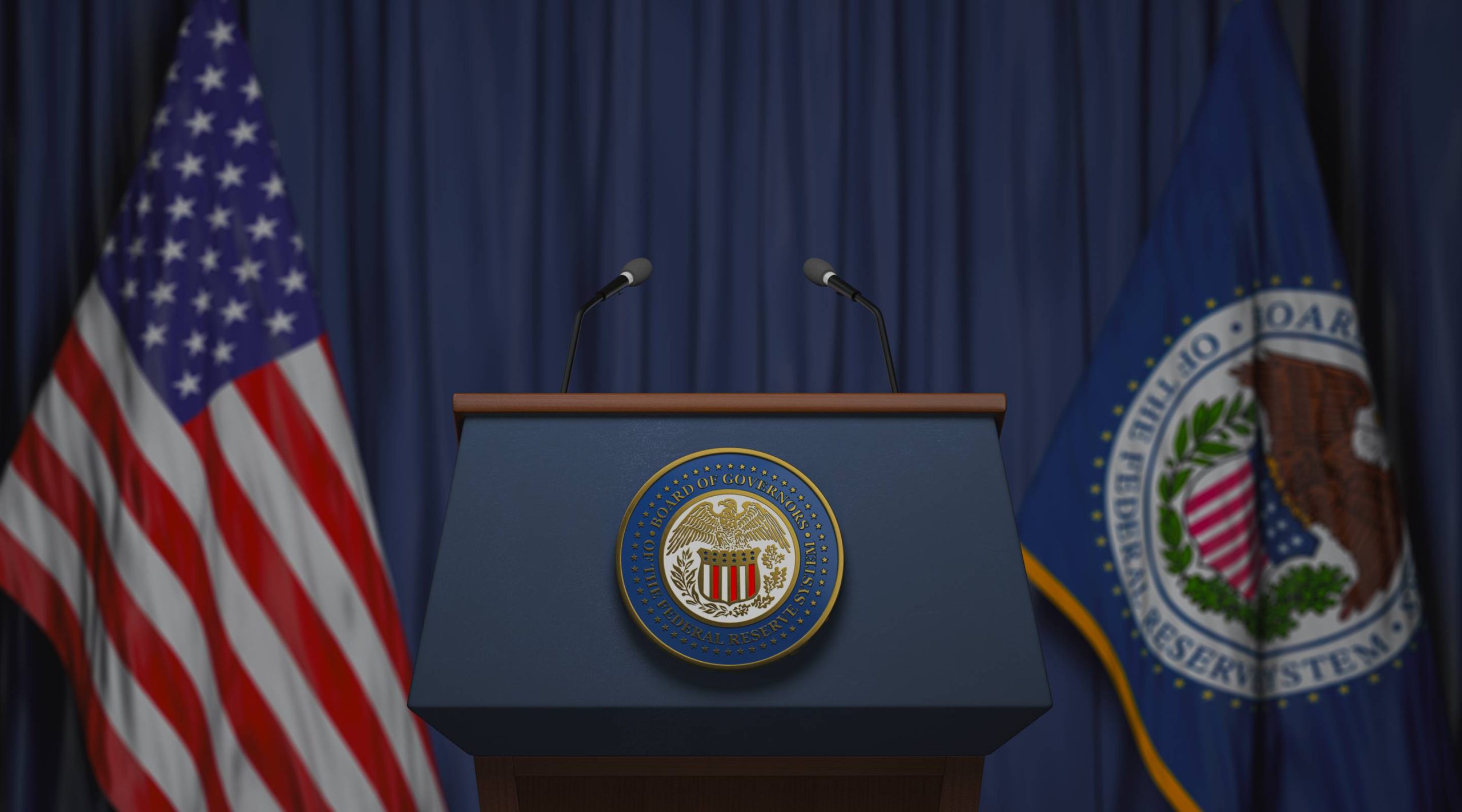 A podium with the Federal Reserve seal sits between microphones, with the American flag and Federal Reserve flag in the background.